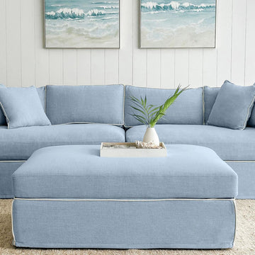 Contemporary upholstered ottoman in beach fabric with white trim and wooden legs for elegant lounge seating