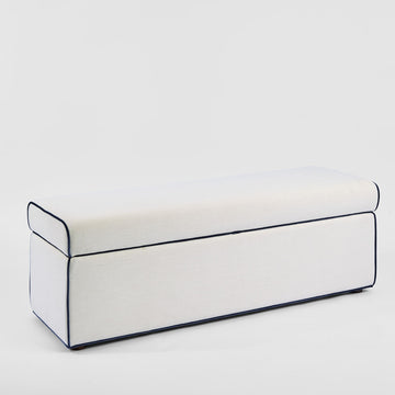 Ivory upholstered storage ottoman with blue piping detail and hidden compartment for luxury bedroom furniture